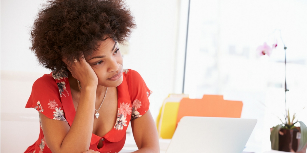A bored woman sitting at her desk in front of a computer