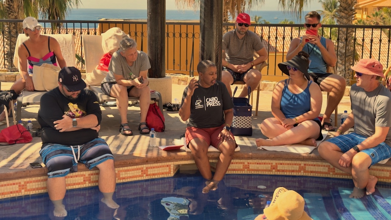 2022_10_06_kronda_adair_presenting_cabopress_01 Kronda Adair sitting at the edge of a resort swimming pool presenting a talk on marketing automation at CaboPress